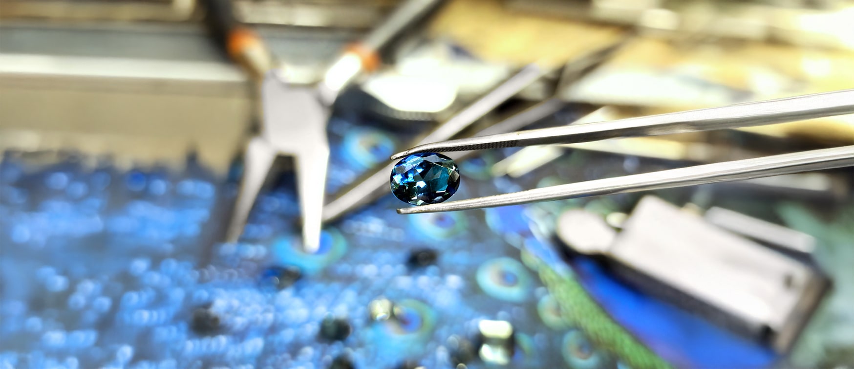 Loose Blue Sapphire Held in Tweezers at Mark Solomon Jewellers