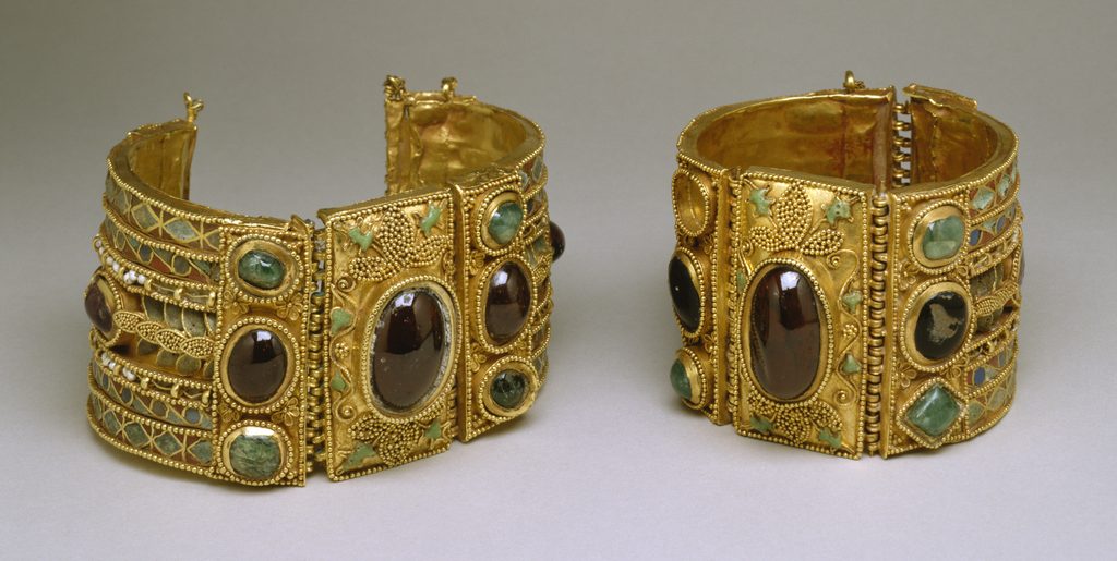 Pair of Ornate Gold Bracelets with Large Oval Stones and Green Enamel Insets, Displayed Side by Side on a Neutral Background, Jeweled and Intricate in Design.