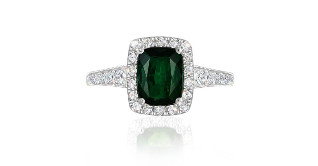 This enchanting Green Tourmaline Diamond Halo Ring heralds a deep, verdant green tourmaline (chrome tourmaline totalling 1.471ct with EGL Certification), surrounded by a glittering halo of micro-set small round brilliant cut white diamonds, with diamonds extending down the sides of the band (30 diamonds totalling: 0.34ct, G-H colour VS-SI clarity).

Handcrafted by our Master Goldsmiths on our premises using the highest grade 14ct white gold.