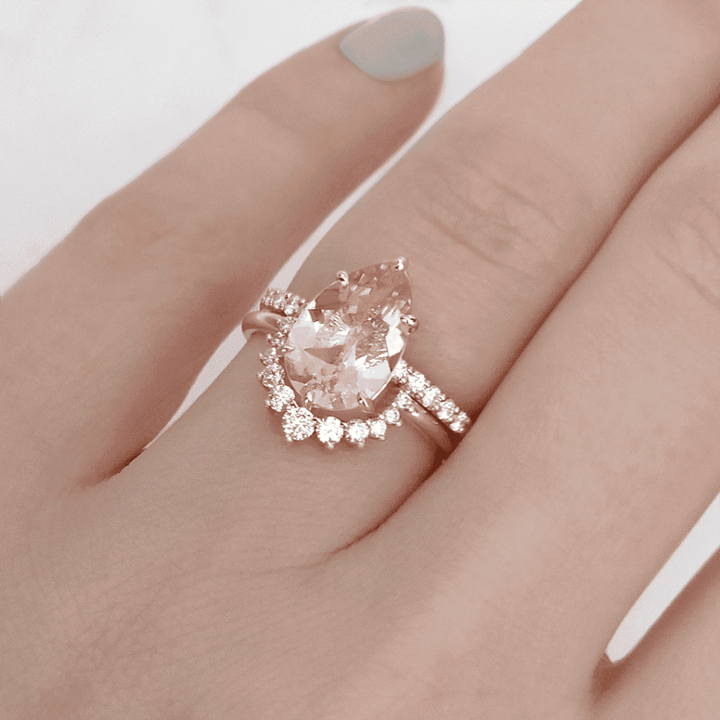 Morganite Pear and Curved Eternity Band 1 1 - Mark Solomon Jewellers Pear-cut Peach Morganite Engagement Ring in 18ct Rose Gold Paired with a Custom Curved Diamond Eternity Band on a Model's Hand.