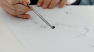 A jewellery designer sketching out the design for the Rare Africa neckpiece, using a rare tsavorite to compare shapes and sizes