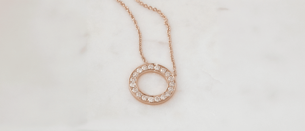 Post 4 Creating Unique and Meaningful Custom Jewellery 1 - Mark Solomon Jewellers Bespoke 18ct Rose Gold Diamond Circle Pendant Necklace Resting on White Marble at Mark Solomon Jewellers.