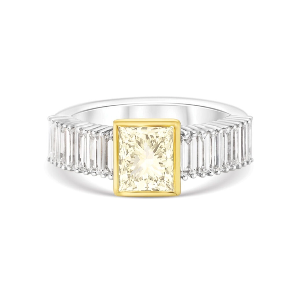 a Modern Ring Featuring an Emerald Cut Light Yellow Diamond Bezel-set in Yellow Gold. the Band is Channel-set with Baguette-cut White Diamonds in White Gold or Platinum.