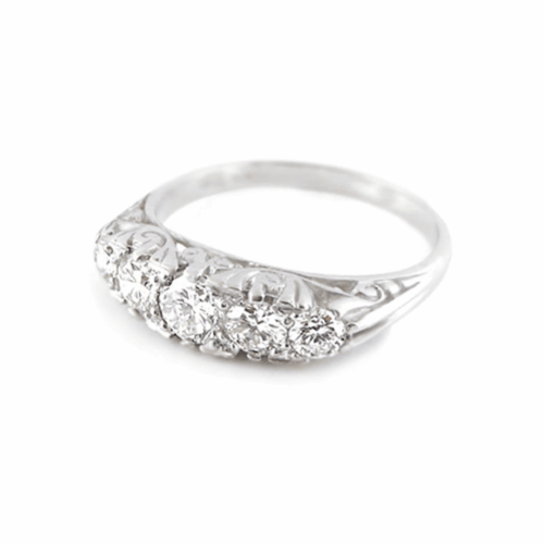 Vintage-style white gold or platinum five-stone diamond ring with scrollwork engraving and round brilliant diamonds.