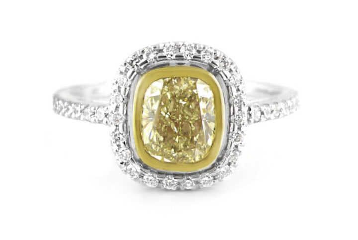 a Stunning Cushion-cut Fancy Yellow Diamond Ring. the Center Stone is Bezel-set in Yellow Gold and Surrounded by a Halo of White Diamonds. the Band is Also Set with White Diamonds in White Gold or Platinum.