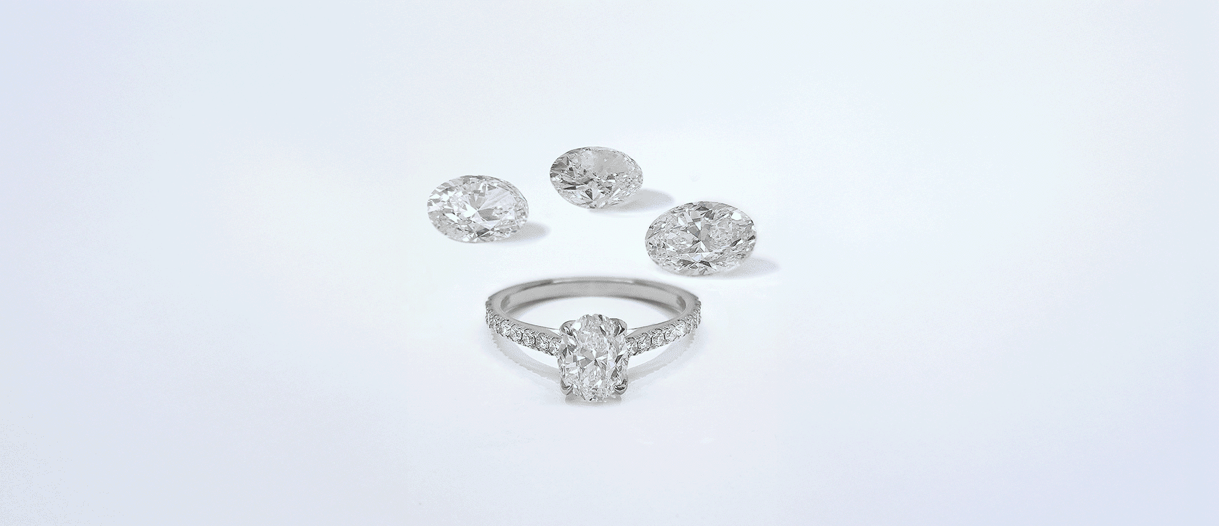 Oval Diamond Engagement Ring in White Gold Displayed with Three Loose Oval-cut Diamonds on a Clean, Light Background.