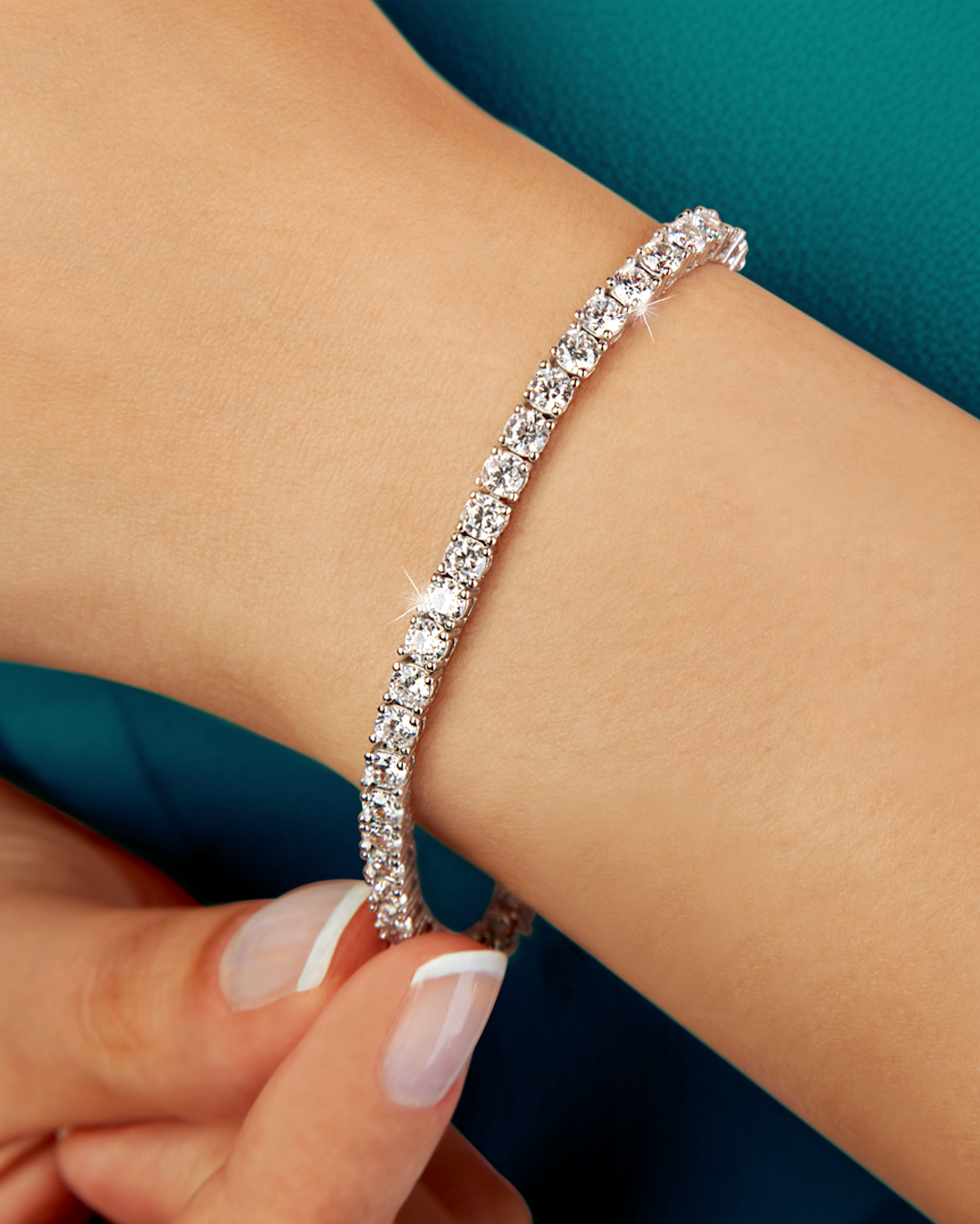 Close-up of a Hand Fastening a White Gold Tennis Bracelet Set with Round Diamonds on a Wrist.